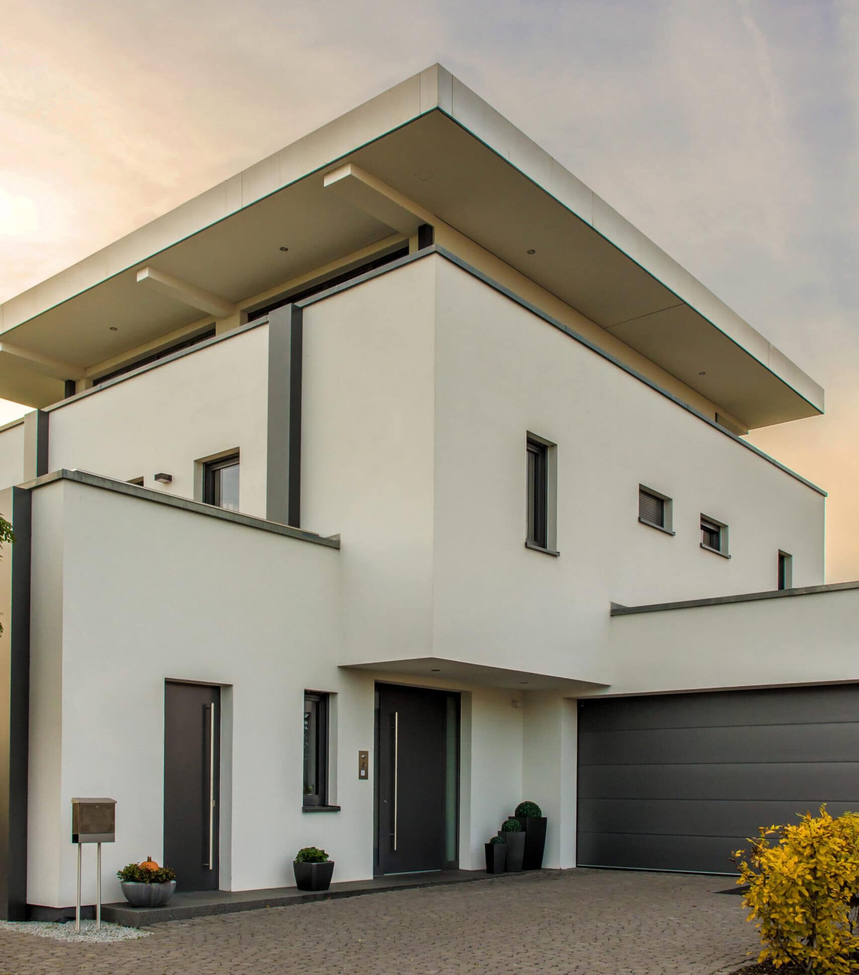 Moderne weiße Villa mit Balkon, großem Eingang und Garage, ideal für Familien in ruhiger Lage.