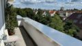 Heller Balkon mit Sitzgelegenheiten und Blick auf Landau bei schönem Wetter.