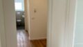 Flur in einer modernen Wohnung mit Holzfußboden und Zugang zum Badezimmer.
