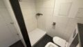 Modernes Badezimmer mit Dusche, WC und weißen Fliesen.