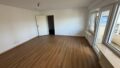 Geräumiges, helles Wohnzimmer mit großen Fenstern und Holzboden.
