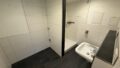 Modernes Badezimmer mit Dusche, Waschbecken und weißen Fliesen.
