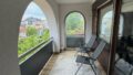 Stilvoller Balkon mit Blick auf die Stadt und grüne Bäume.