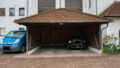 Stellplatz mit Carport, Fahrrad und Auto vor Wohngebäude.