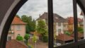 Blick durch ein Fenster auf eine ruhige Wohnstraße mit Bäumen und Häusern.